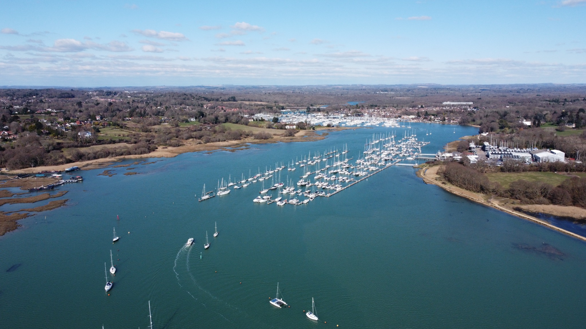 Aerial view over a winding waterway and rows of moored boats